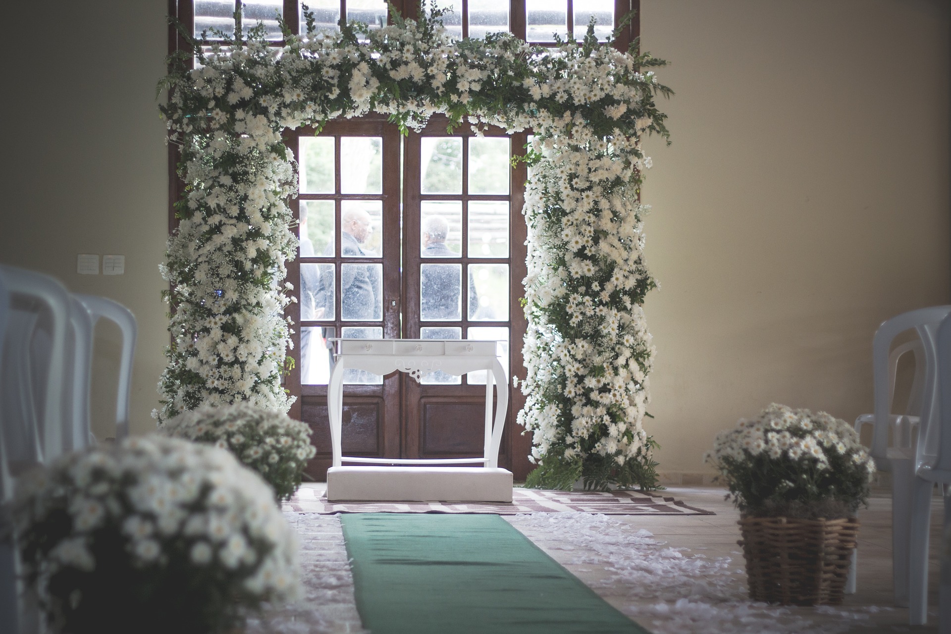 white floral wedding arch over white wooden altar for a wedding